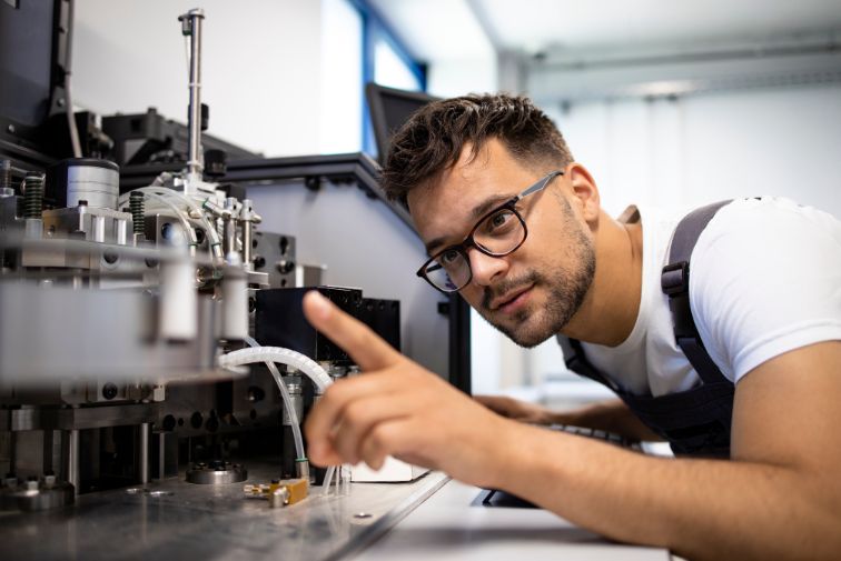A young man looking closely at a paper manufacturing machine